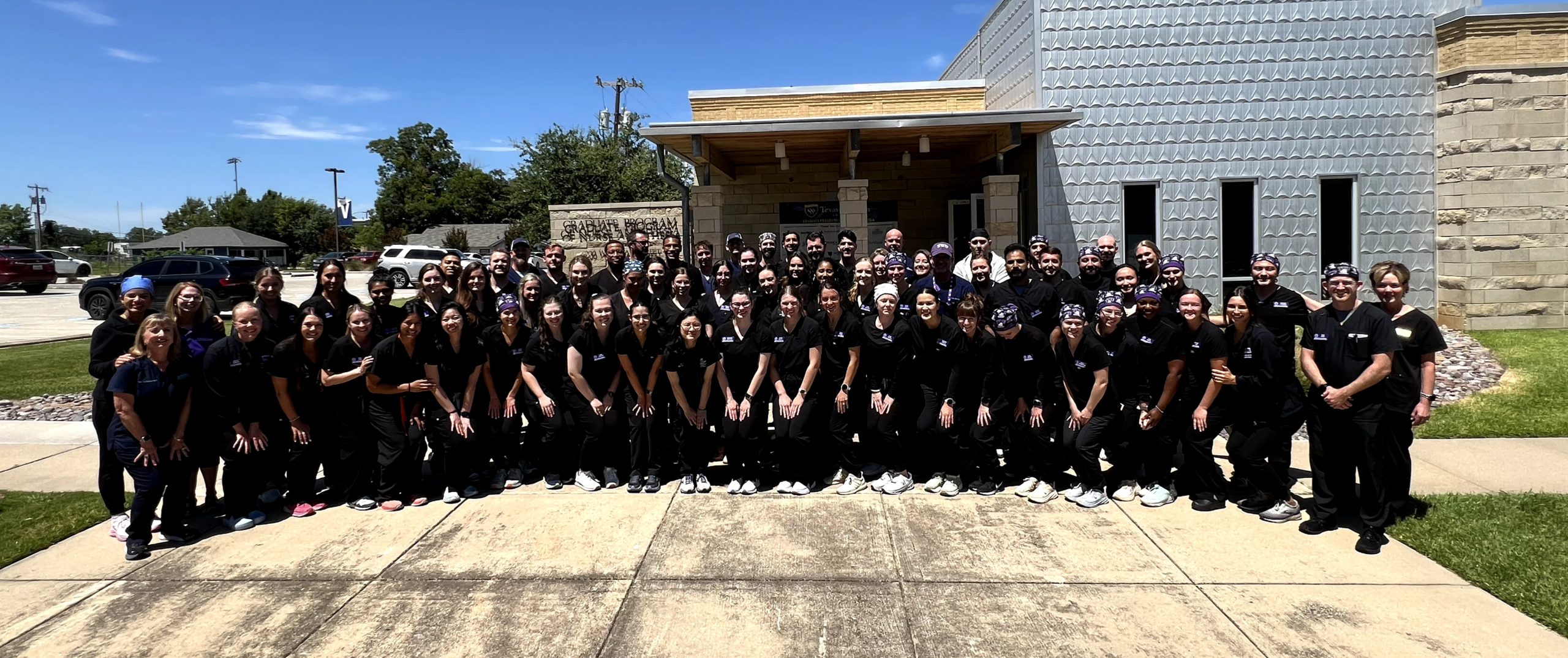 IMG_6058 Group photo of doctors in navy blue scrubs standing together outside a medical facility.