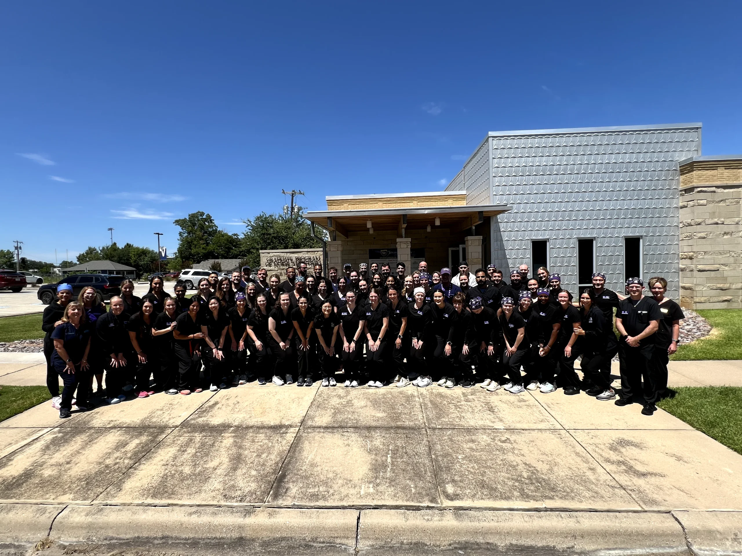 Group photo of doctors in navy blue scrubs standing together outside a medical facility.